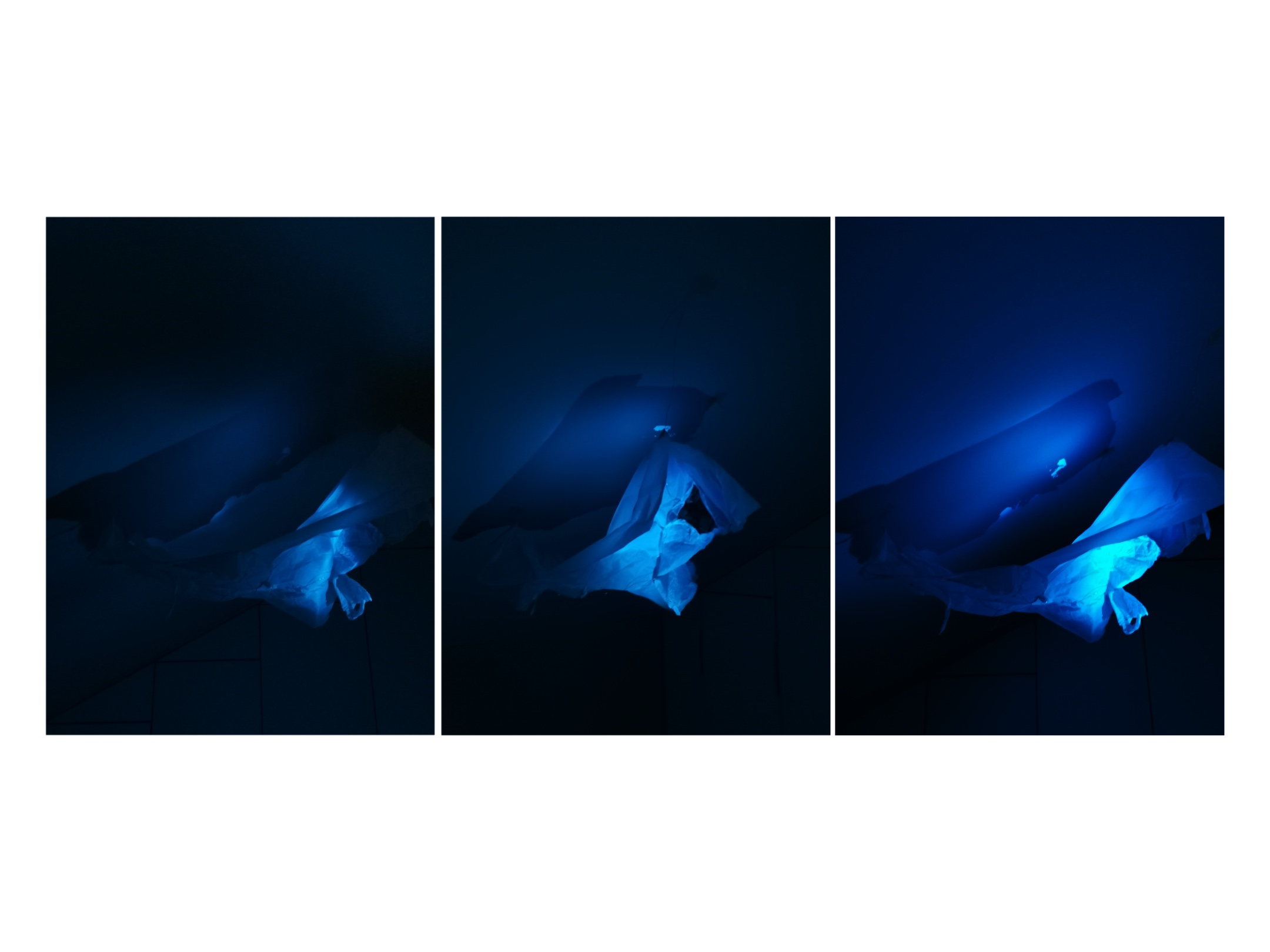 three images of paper models lit my torch at night cast in blue